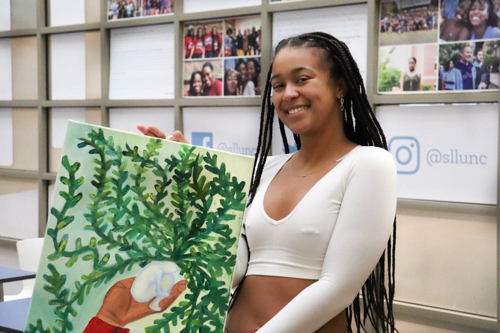 UNC sophomore and member of Earthtones, Kennedy Hall, is pictured with art she painted for the club on Sunday, Jan. 8, 2023, in the Student Union.