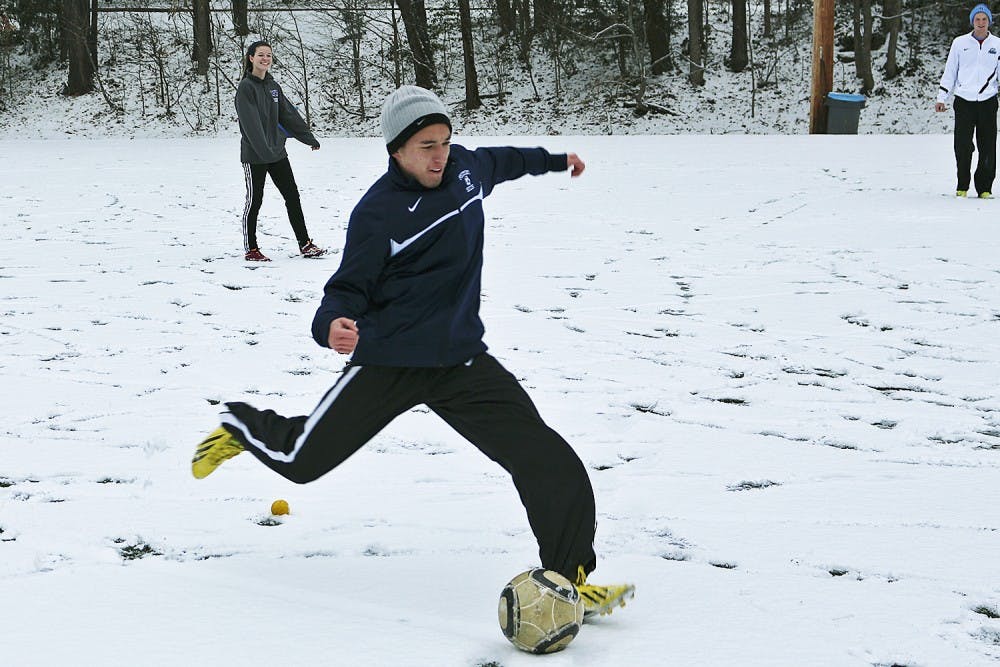 <p>Freshmen Trevor Doane (right) and Megan NcNeill play soccer in the snow on Ehringhaus fields Tuesday. Classes were canceled at 2:30 p.m.</p>