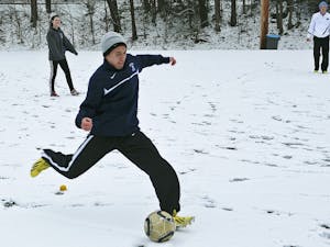 Freshmen Trevor Doane (right) and Megan NcNeill play soccer in the snow on Ehringhaus fields Tuesday. Classes were canceled at 2:30 p.m.