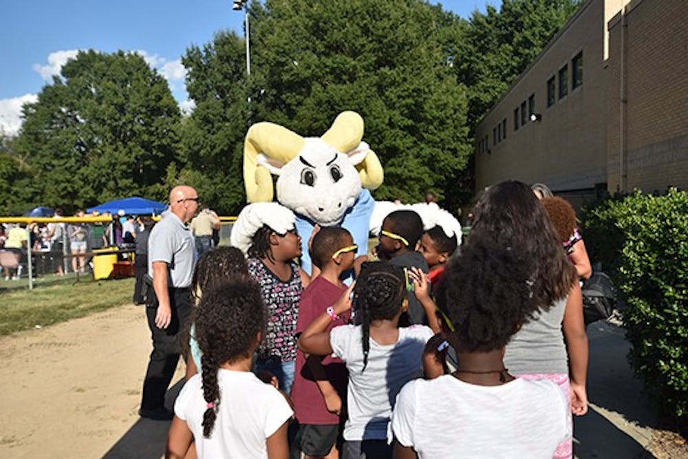 Ramses embraces a group of local children at the good neighbor block party at Hargraves Community Center on Tuesday evening. 