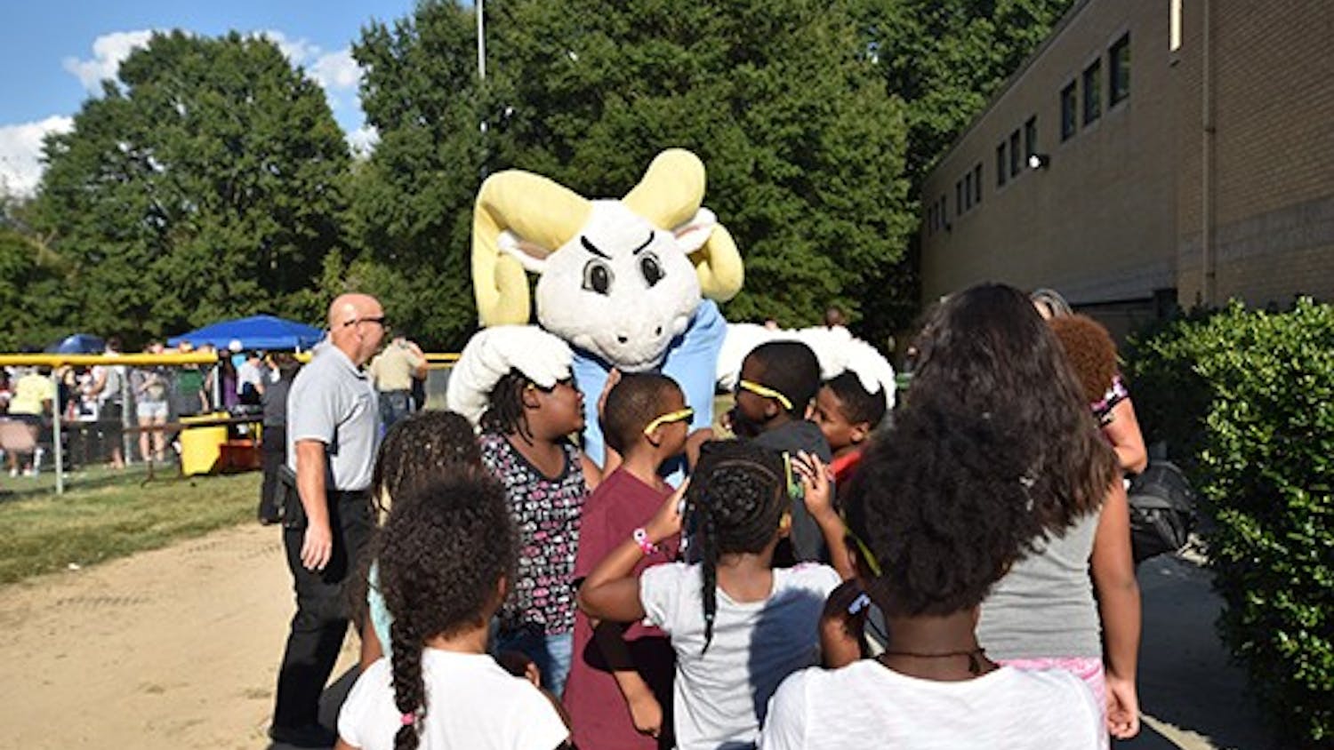 Ramses embraces a group of local children at the good neighbor block party at Hargraves Community Center on Tuesday evening. 