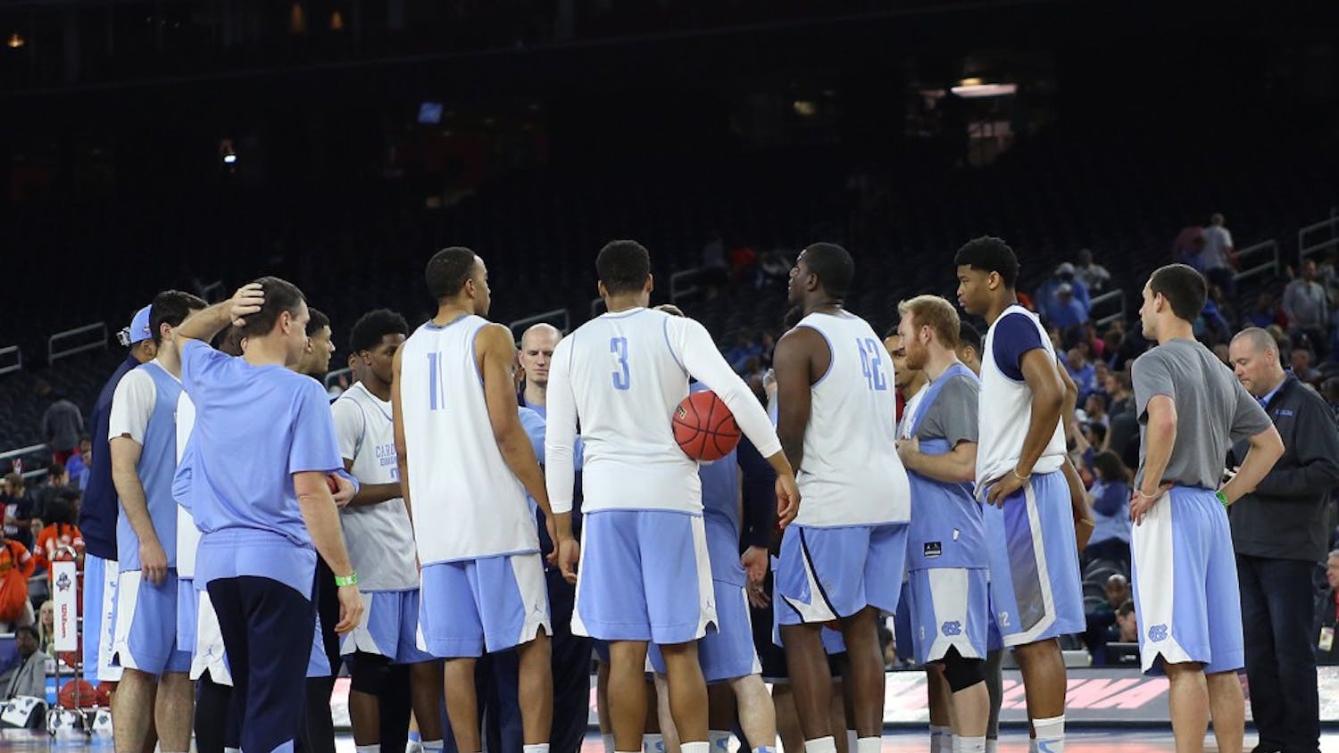 The UNC men's basketball team huddles up at center court.