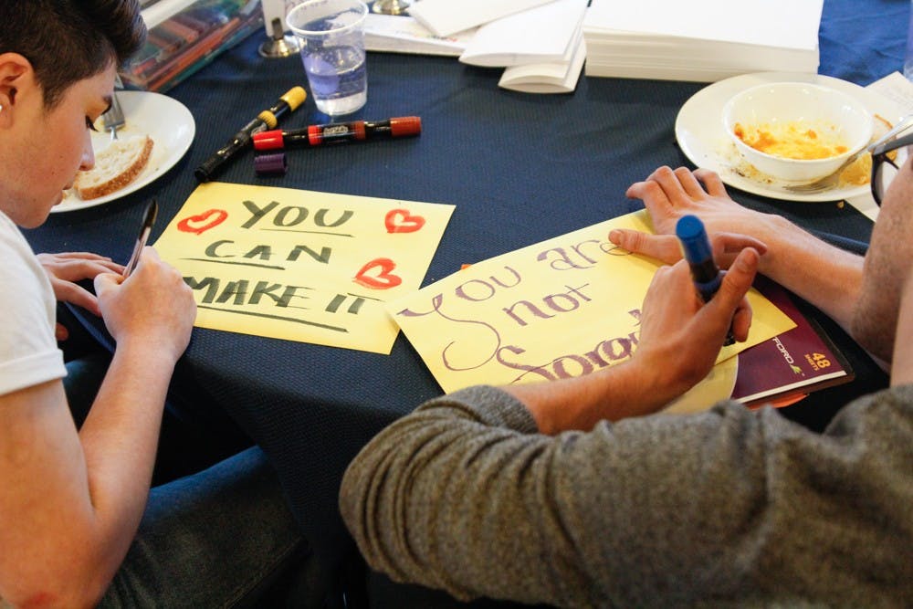 (From left to right) Gaby Taccir, visual designer at R65 labs and Chris Corsi, program assistant at UNC Student Wellness, write letters for Kanautica Zayre-Brown at the Queer Family Gathering dinner at a community building in Carrboro, Tuesday, March 19, 2019. Kanautica is a trans woman incarcerated at a men's prison and who has been in solitary confinement for 17 days. The letters are meant to help Kanautica maintain her mental health during her confinement until she can be moved into a women's facility.