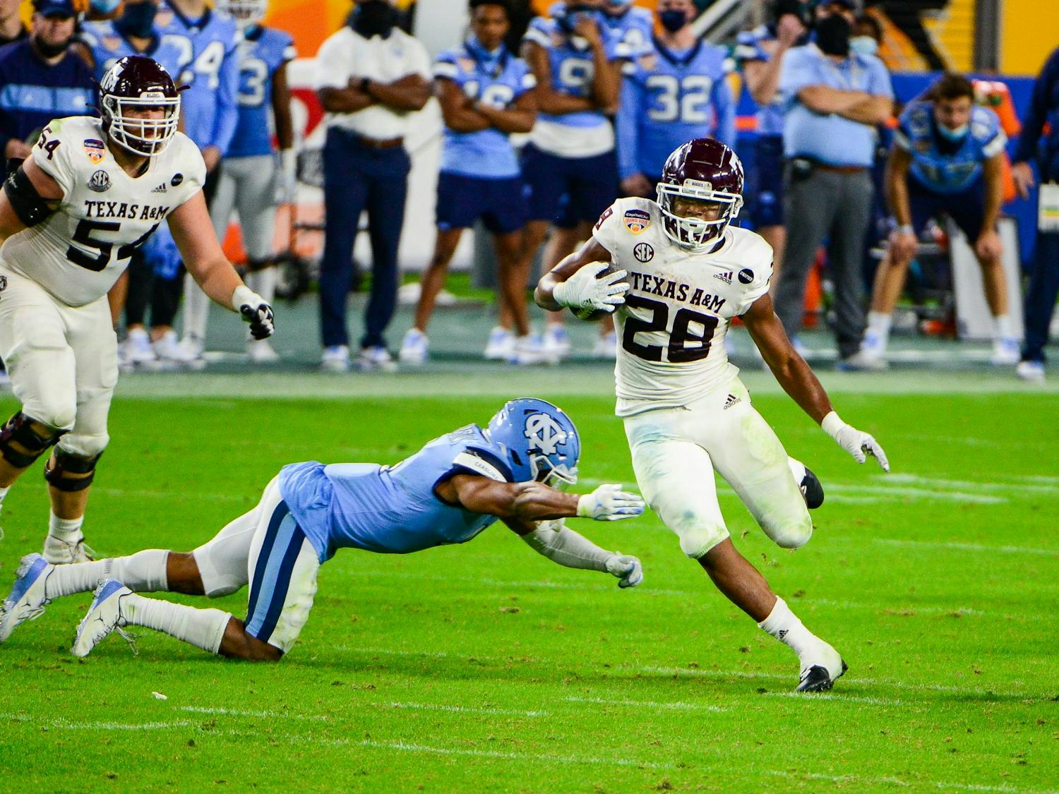 Texas A&M's sophomore running back Isaiah Spiller (28) evades UNC's junior defensive back Trey Morrison during the Capitol One Orange Bowl in Hard Rock Stadium in Miami on Saturday, Jan. 2, 2021.  Texas A&M beat UNC 41-27.