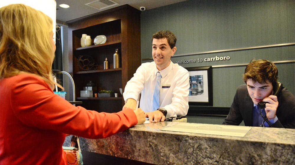 Hampton Inn & Suites General Manager Kevin Rooney talks with Katie Henning, Sales Manager, while Jack Bowen, Front Desk Agent, takes calls.