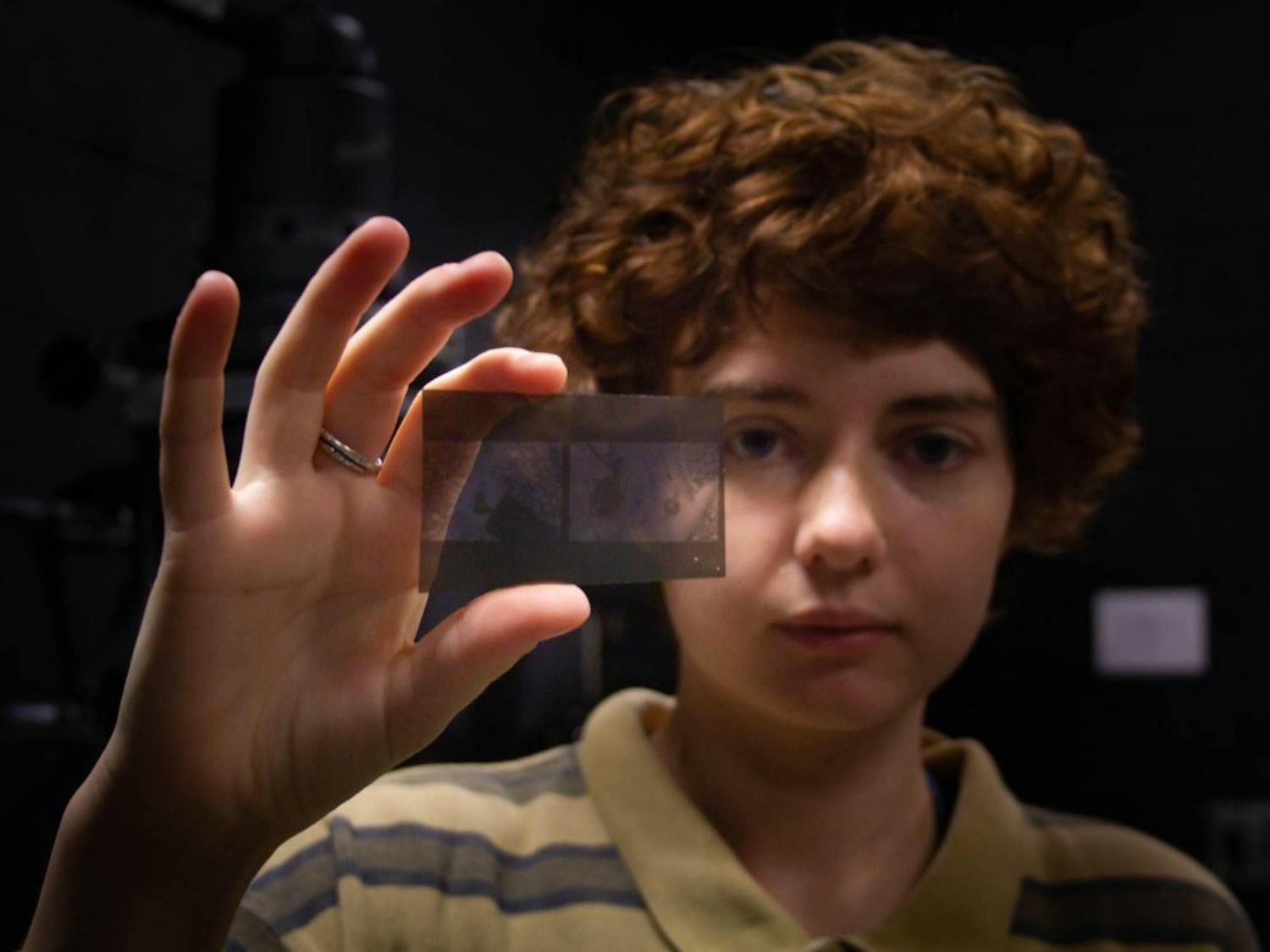 Sophie Payne, a sophomore English major at UNC, holds a lithofilm negative which she will use to get higher contrast in her final enlargened print in an advanced Darkroom Photography class on Thursday, Oct. 10, 2019. "I always push my film which means that my film has more contrast. I like blacks and whites, I don't like as many greys. So, a lot of my images are intense," Payne said.