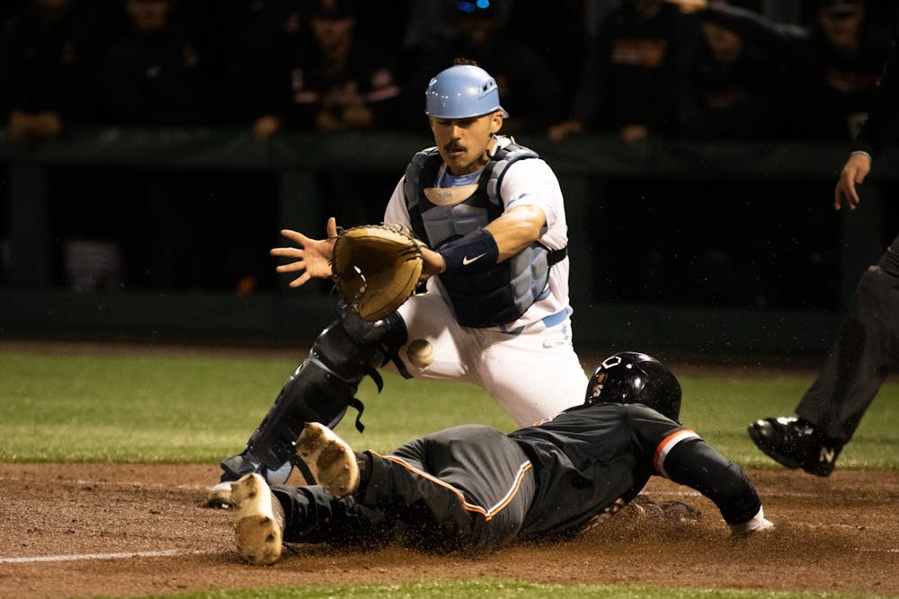 A Fighting Camel slides into home to score past UNC sophomore catcher Thomas Frick's (52) waiting glove during a baseball game at Boshamer Stadium on Tuesday, April 19, 2022.