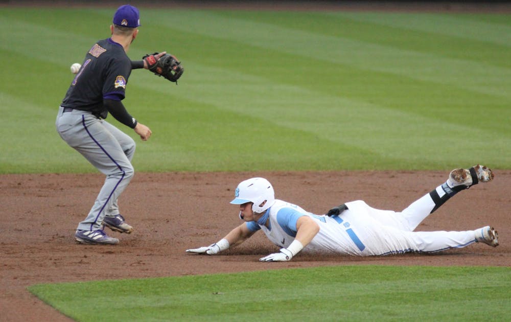 UNC junior right-handed pitcher Michael Oh (1) attempts to slide into first base before getting tagged out by ECU infielder Connor Norby during the Tar Heels' game against East Carolina University at Boshamer Stadium on March 23, 2021. The Tar Heels defeated the Pirates 8-1.