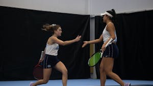 Junior Fiona Crawley high-fives sophomore Carson Tanguilig during their doubles match against Elon University at the Cone-Kenfield Tennis Center on &nbsp;Friday, Jan. 13, 2023. UNC beat Elon 4-2.