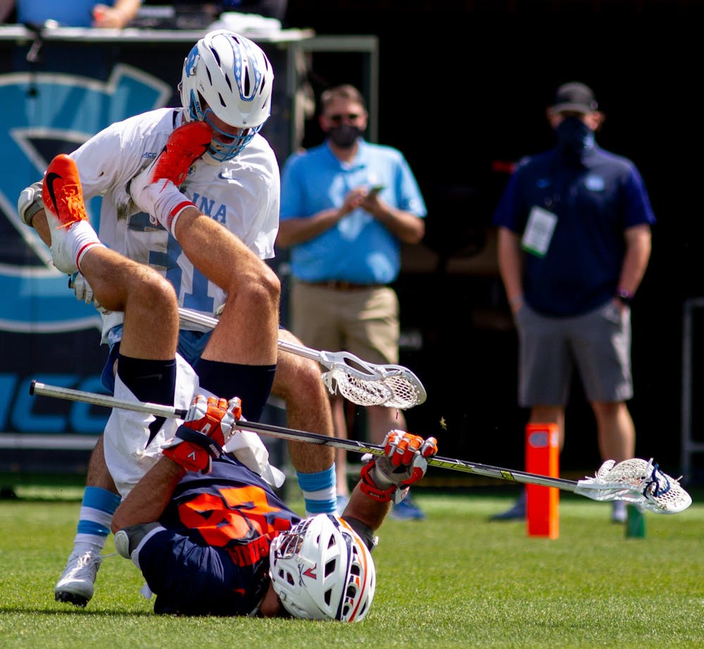 Junior defensive midfielder Connor Maher (31) collides with UVA's Jared Conners shortly after a faceoff during Carolina's 18-16 loss at Dorrance Field in Chapel Hill on April 10, 2021.