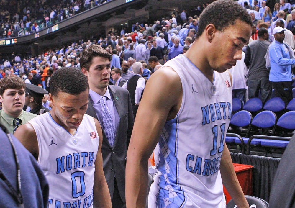Brice Johnson and Nate Britt hang their heads as they exit the court after UNC lost to Pittsburgh 80-75 in the ACC Tournament at the Greensboro Coliseum.
