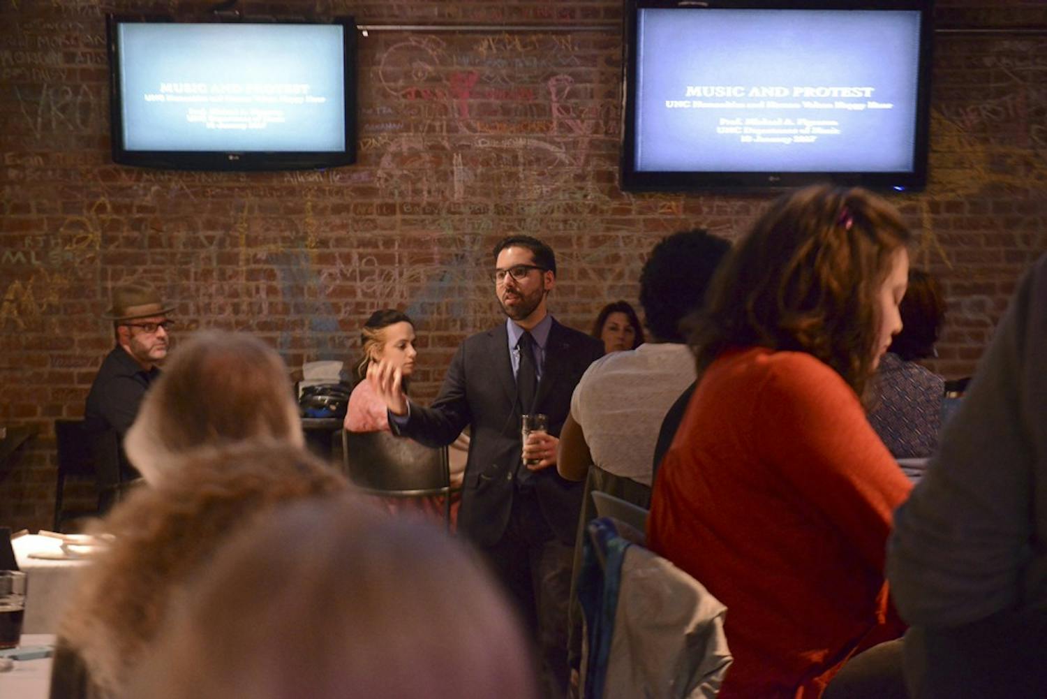 Michael Figueroa, an ethnomusicologist, gives a speech at the Humanities Happy Hour: Protest Music event on Wednesday night at Top of the Hill.