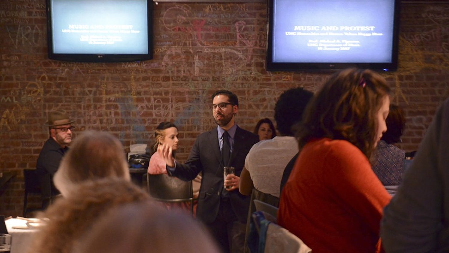 Michael Figueroa, an ethnomusicologist, gives a speech at the Humanities Happy Hour: Protest Music event on Wednesday night at Top of the Hill.