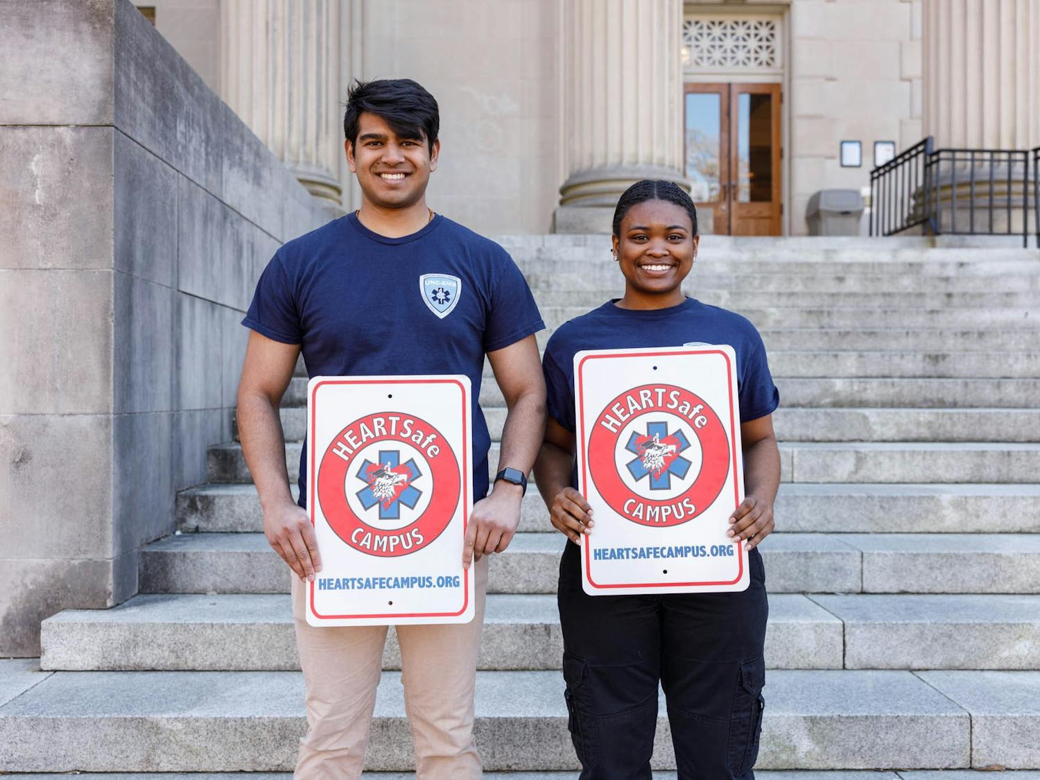 Advanced EMT Kirti Patel (left) and EMT Jayla Cobbs (right), who led the effort in getting UNC's HEARTSafe Campus accreditation, pictured holding up signs that will be put up around campus.