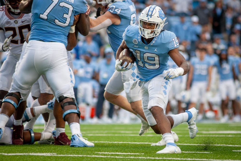 UNC graduate running back Ty Chandler (19) sneaks past a pack of defenders during the Tar Heels' home football game in Kenan Stadium on Oct. 9. FSU won 35-25.
