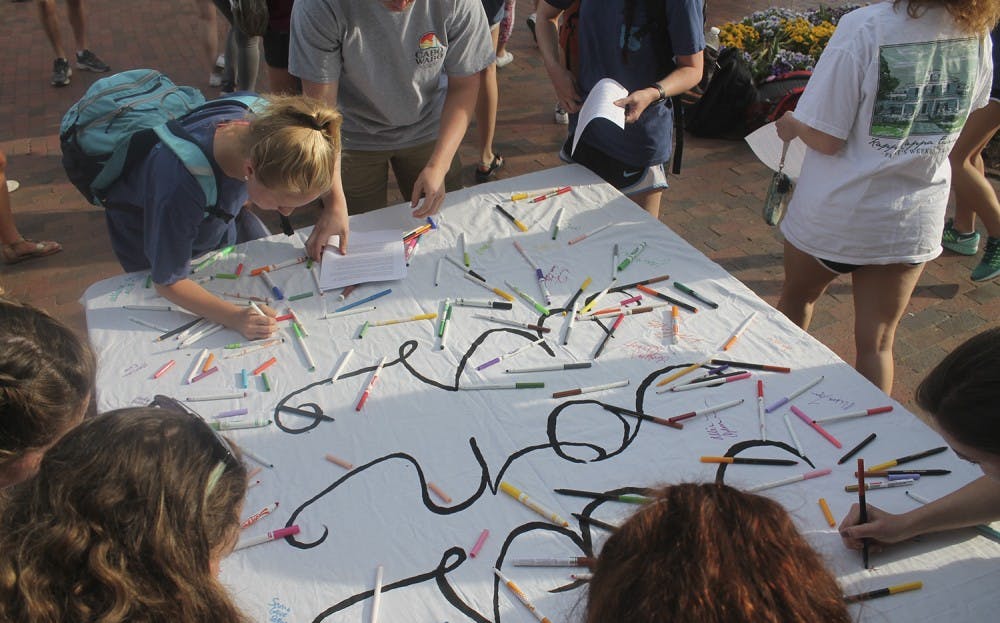 Students sign the "it's on us" banner to demonstrate taking responsibility to stop sexual assault