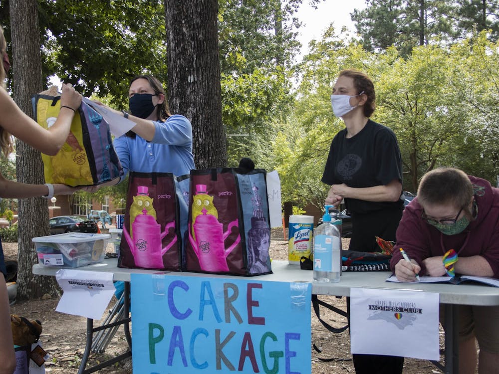 (From left) Lynne Privette, Jamie Sohn and Tiz Giordano hand out care packages to a first-year outside of the George Watts Hill Alumni Center on Wednesday, Sep. 16, 2020 through Chapel Hill/Carrboro Mothers Club. Over 35 students received personalized packages and community members made 75 homemade masks in support of the initiative. "The average care package weighed about seven pounds," Sohn said.