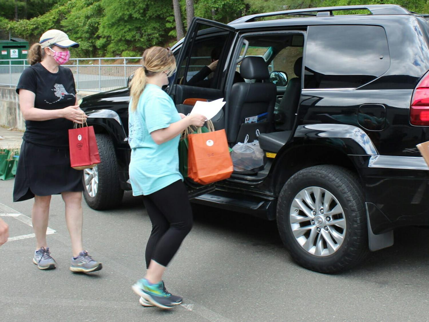 Volunteers for Book Harvest load food and books into cars to be delivered to families across Durham in a collaborative effort with the Durham Public Schools Foundation and Durham FEAST.