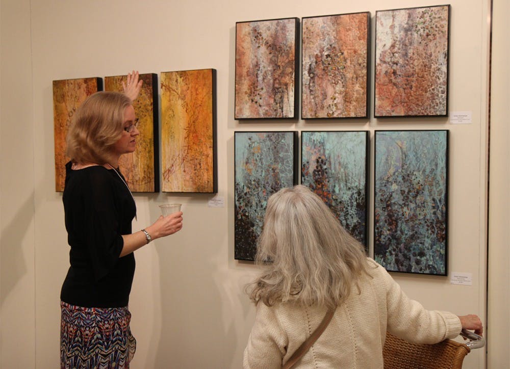 	Shelly Hehenberger, one of FRANK’s consignment artists, discusses her mixed media artwork with a visitor of the “Let’s Be FRANK” exhibition.