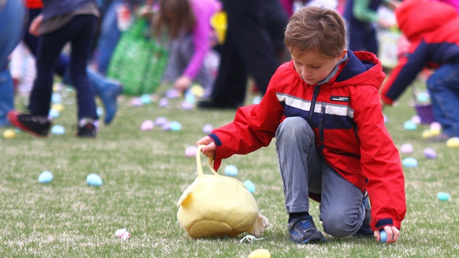 A child picks up easter eggs to put in his easter basket on Sunday.