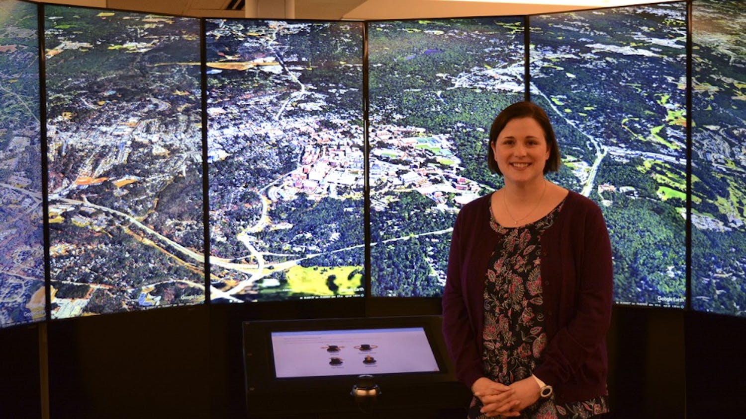 Amanda Henley stands in front of Davis Library's Liquid Galaxy, with the city of Chapel Hill pictured.