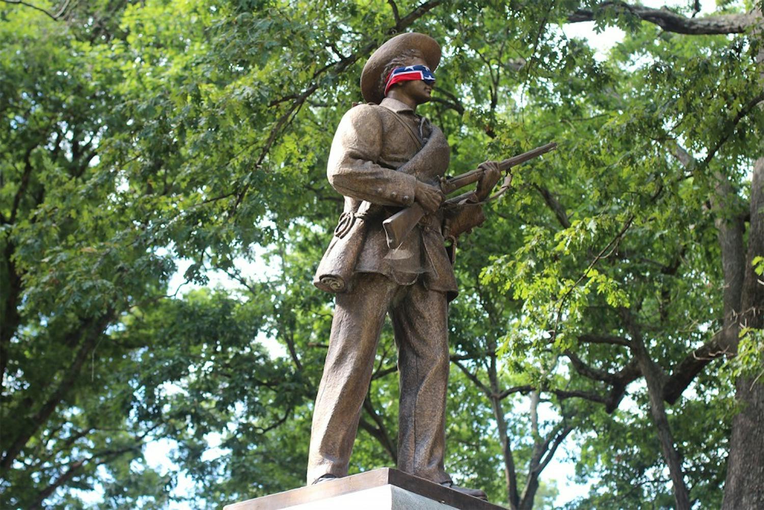 Silent Sam blindfolded by a Confederate flag in 2015. The statue was recently given to Sons of Confederate Veterans.