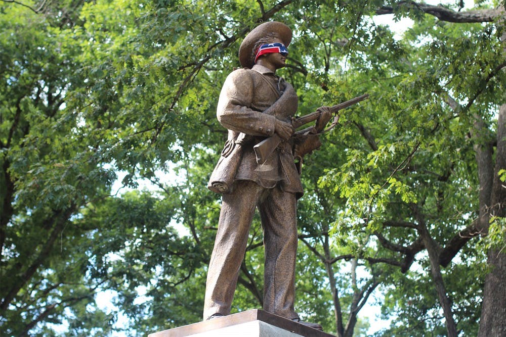 Silent Sam blindfolded by a Confederate flag in 2015. The statue was recently given to Sons of Confederate Veterans.