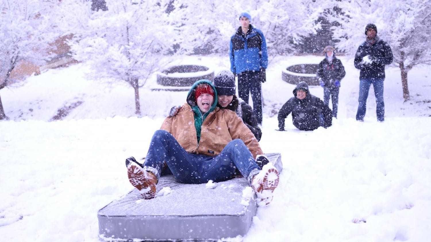 First-years Grantito Everist (left) and Cat Chang (right) use a mattress to sled down the hill at the Dean Smith Center during Wednesday's snowstorm.