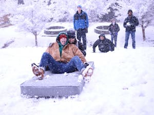 First-years Grantito Everist (left) and Cat Chang (right) use a mattress to sled down the hill at the Dean Smith Center during Wednesday's snowstorm.