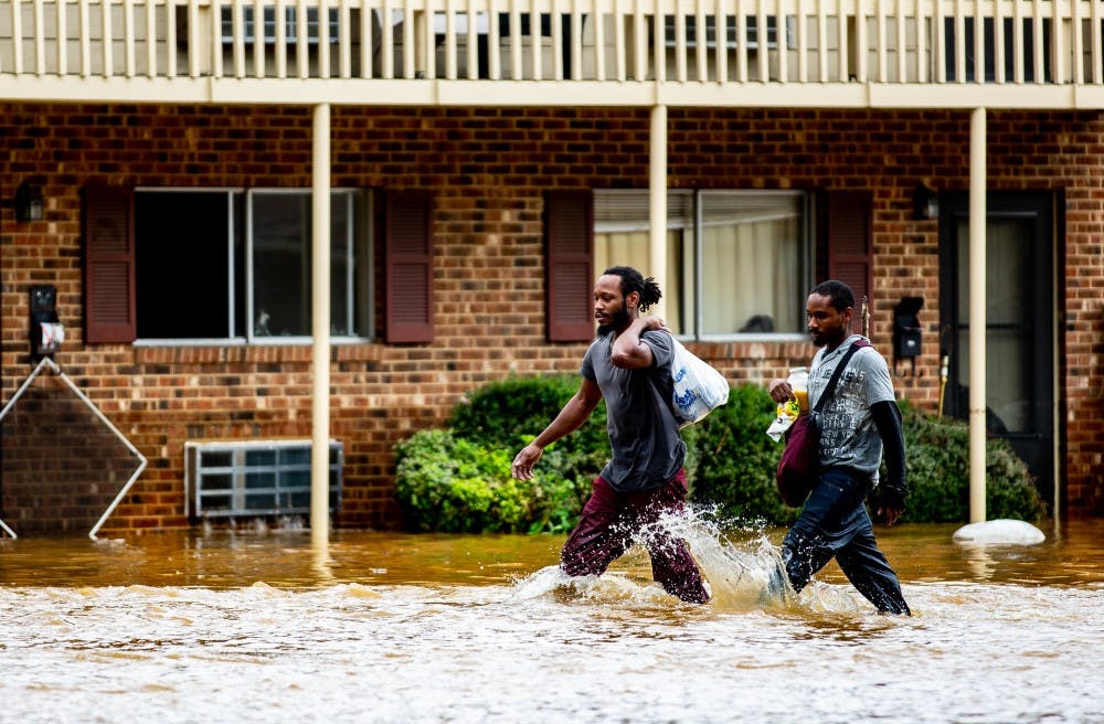 <p>Kyrie and Michael Benton carry food and some of their waterlogged belongings through the grounds of Camelot Village apartments in Chapel Hill the morning of September 17, 2018. Chapel Hill had been seemingly spared the worst of Hurricane Florence but Sunday night into Monday morning saw a downpour of heavy rain that caused flash flooding around the Triangle. Camelot Village has seen flooding in the past but never to this degree, according to Kyrie and other residents of many years. "I lost everything in this flood," Kyrie said. Just as quickly as it flooded, the water began to recede late the same morning and early in the afternoon.</p>