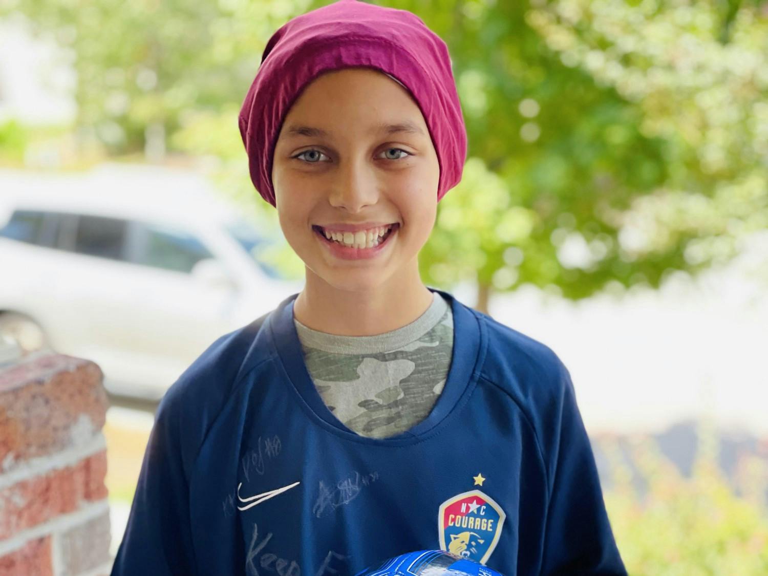 Kaleigh holds a ball signed by United States women’s national soccer team midfielder Julie Ertz and wears an N.C. Courage shirt signed by her teammates. Photo courtesy of Kristin Britton.