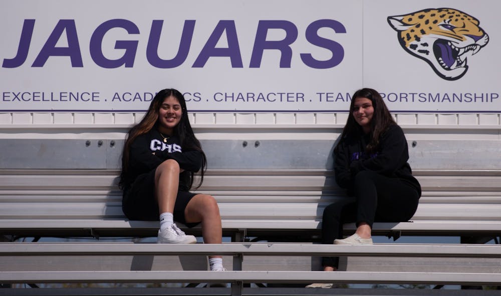 Carrboro High School sophomores Fabiola Perdomo and Sofia Rangel sit in the Carrboro High football stadium. Perdomo and Rangel, like many young people from non-English speaking families, have had to guide their families through participating in school transitions and other difficulties that stem from the pandemic.