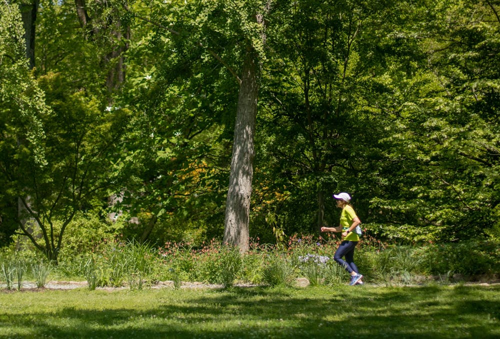 A woman jogs down a trail at the Coker Arboretum on Tuesday, April 18, 2023.
