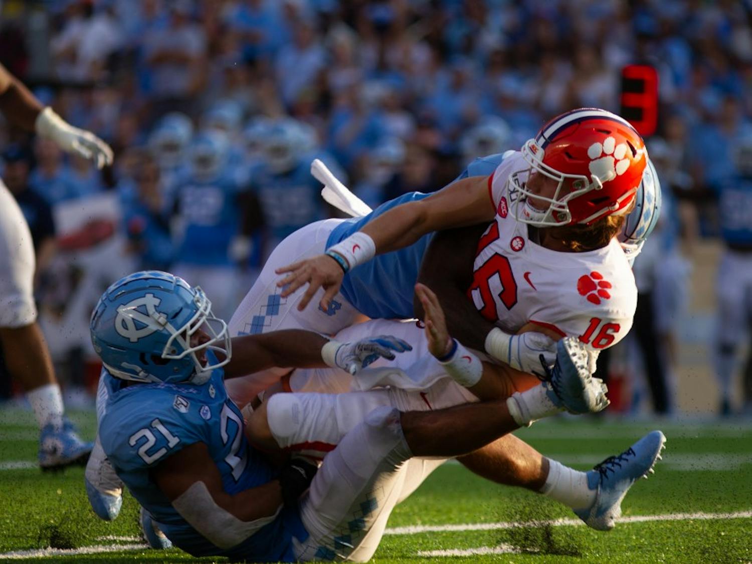 Clemson quarterback Trevor Larwrence (16) is knocked down by UNC linebackers Chazz Surratt (21) and Tomon Fox (12) during the football game on Saturday, Sept. 28th, 2019 at Kenan Memorial Stadium. UNC lost to Clemson 21-20. 