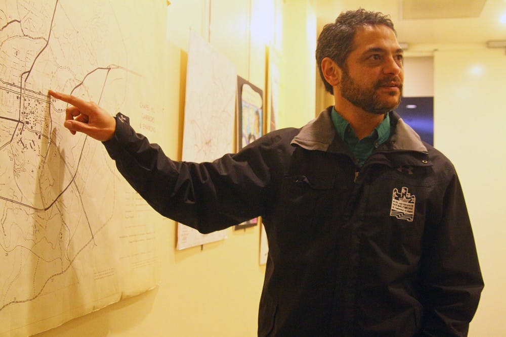 <p>Mark Kleinschmidt points out how Chapel Hill has developed over the years by looking at maps posted in the Chapel Hill Town Hall.</p>