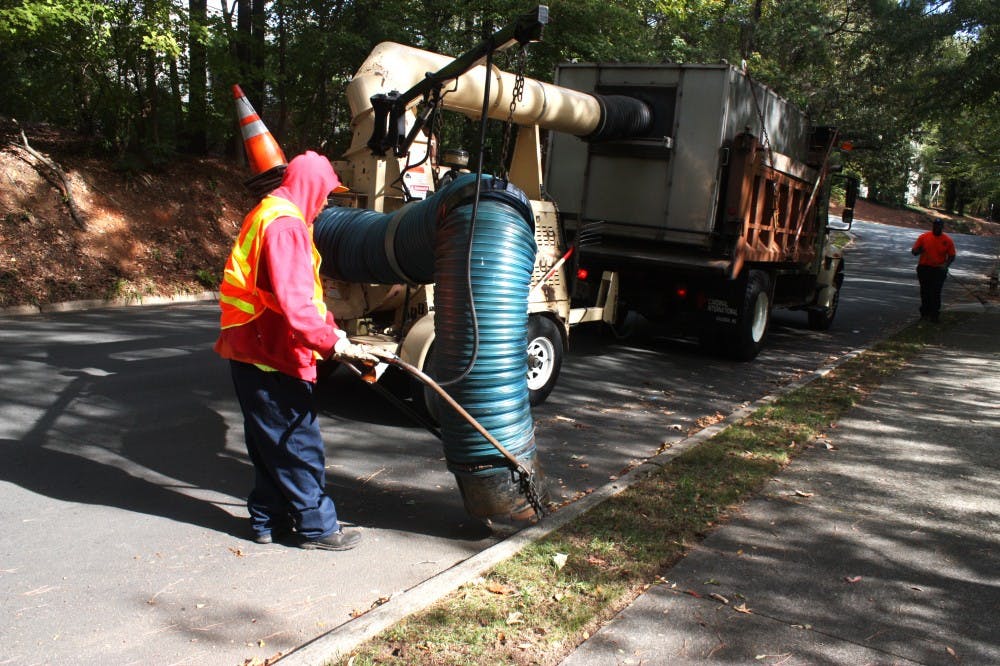 Joe Stiff, a street crew worker for the Town of Chapel Hill Public Works Department, operates a leaf collecting machine on Monday morning as Scott Phillips drives. Monday was the first weekly leaf pickup of the Fall.