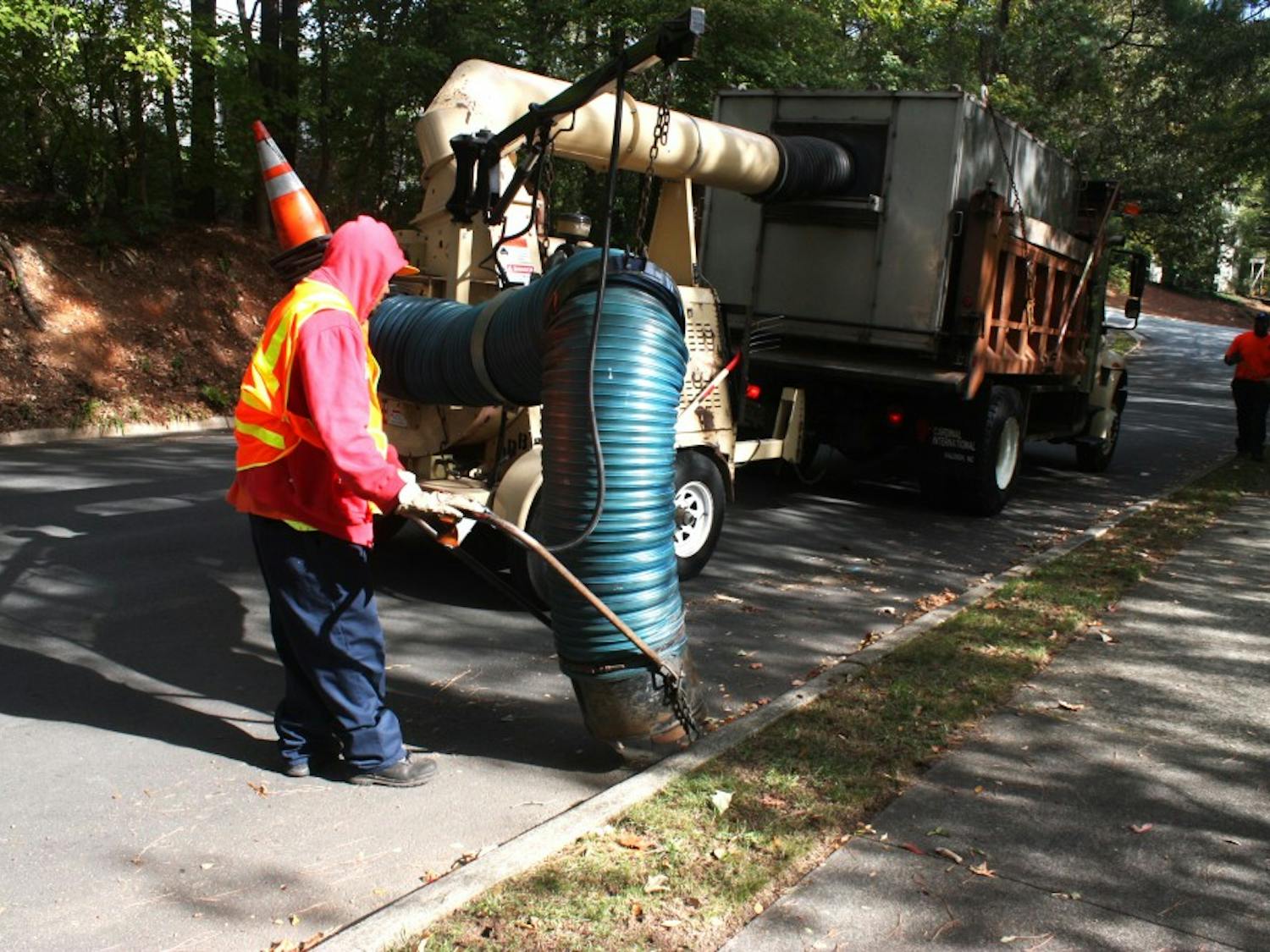Joe Stiff, a street crew worker for the Town of Chapel Hill Public Works Department, operates a leaf collecting machine on Monday morning as Scott Phillips drives. Monday was the first weekly leaf pickup of the Fall.