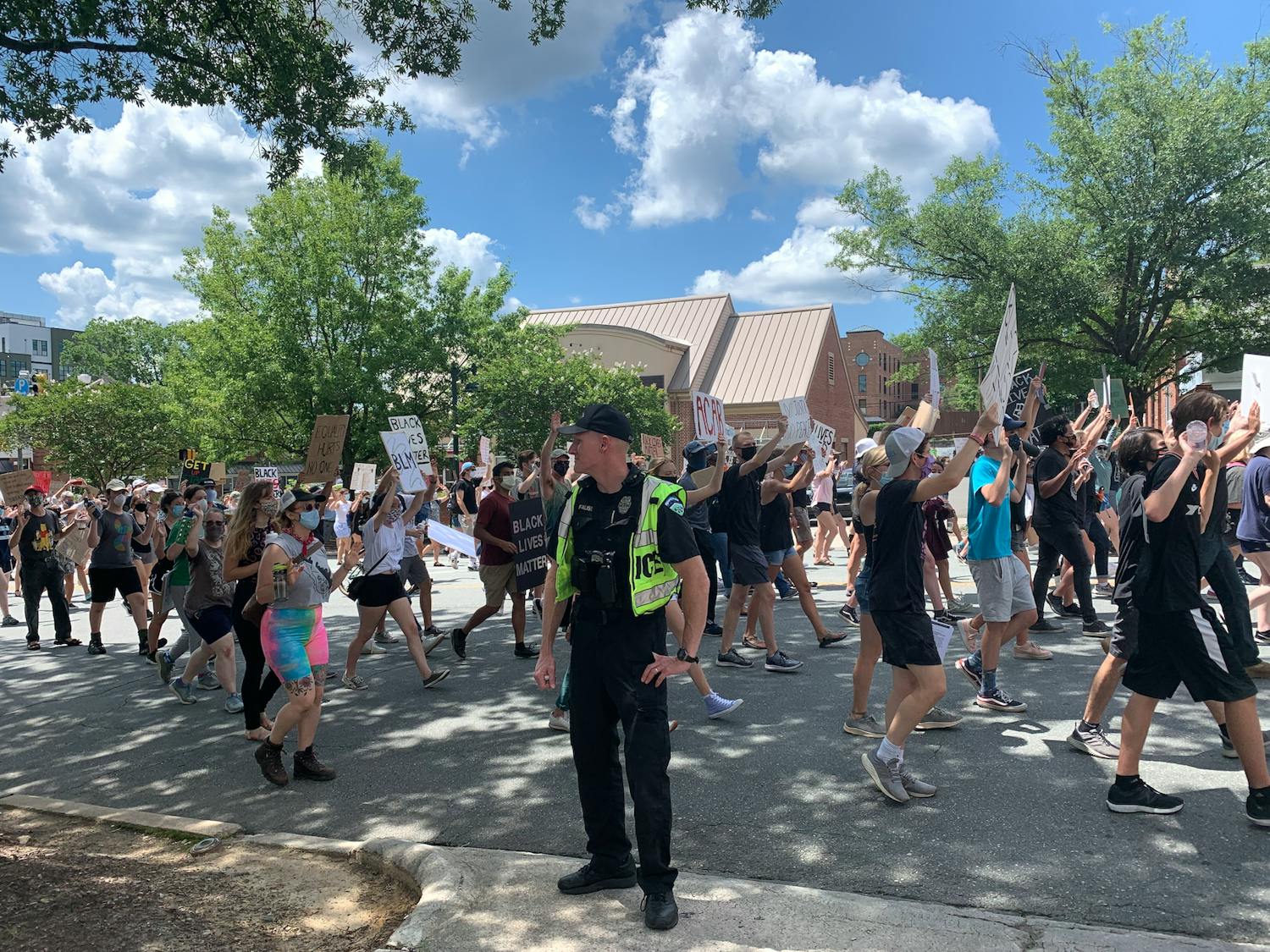 Protestors march past a Police Officer in Chapel Hill on Friday, June 12, 2020 during a protest against police brutality.