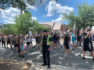 Protestors march past a Police Officer in Chapel Hill on Friday, June 12, 2020 during a protest against police brutality.