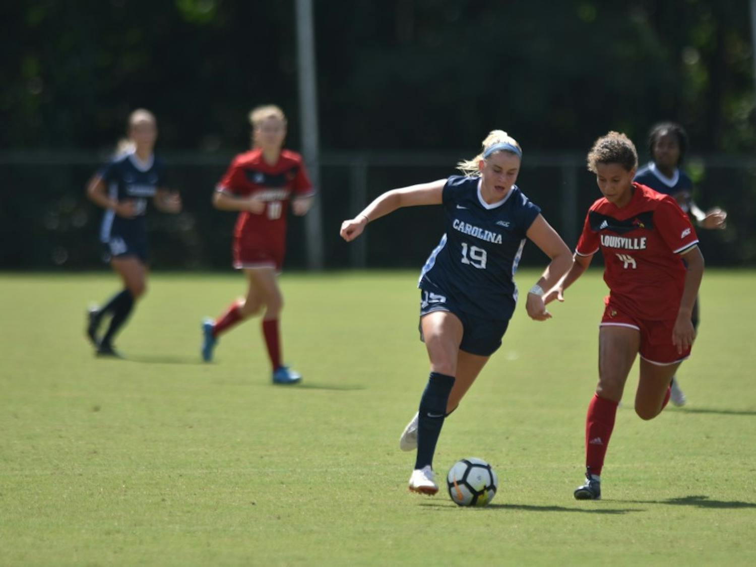 UNC Sophomore Forward Alessia Russo (19) dribbles past Louisville Senior Defender Gabrielle Vincent (14) during  Saturday's game against Louisville at WakeMed Soccer Park. UNC won 5-1