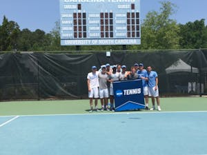 The UNC men's tennis team poses in front of their banner after beating Tennesee on May 13 to move on to the NCAA Sweet 16.&nbsp;