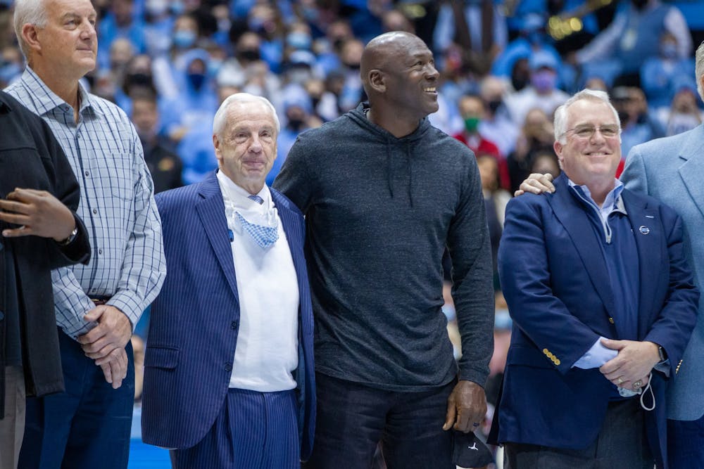 UNC basketball legend Michael Jordan '84 hugs former head coach Roy Williams while the 1982 championship team is honored at the game against NC State at the Smith Center in Chapel Hill on Jan. 29, 2022. UNC won 100-80.