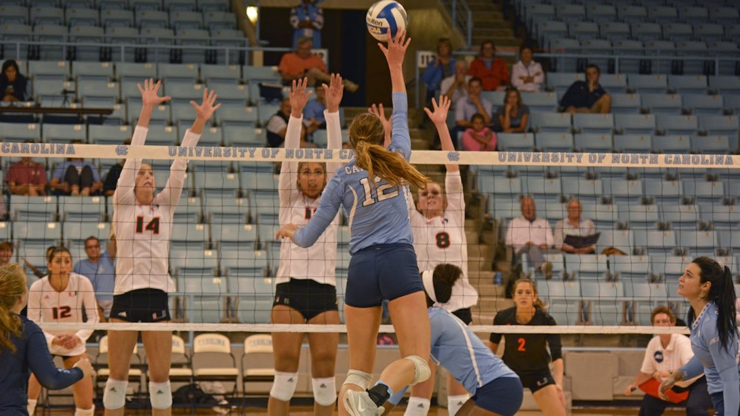 UNC Freshman Julia Scoles (12) spikes the ball against Miami players during the Tar Heels' 3-0 victory over UNC on Sunday, October 9.