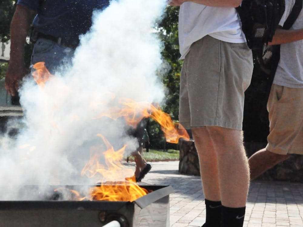 Freshman history major Field Palmer from Clinton, NC extinguishes a fire under close supervision by UNC Fire Marshall Billy Mitchell. Mitchell has worked at UNC for 19 years and has helped with this demonstration for the past three.
