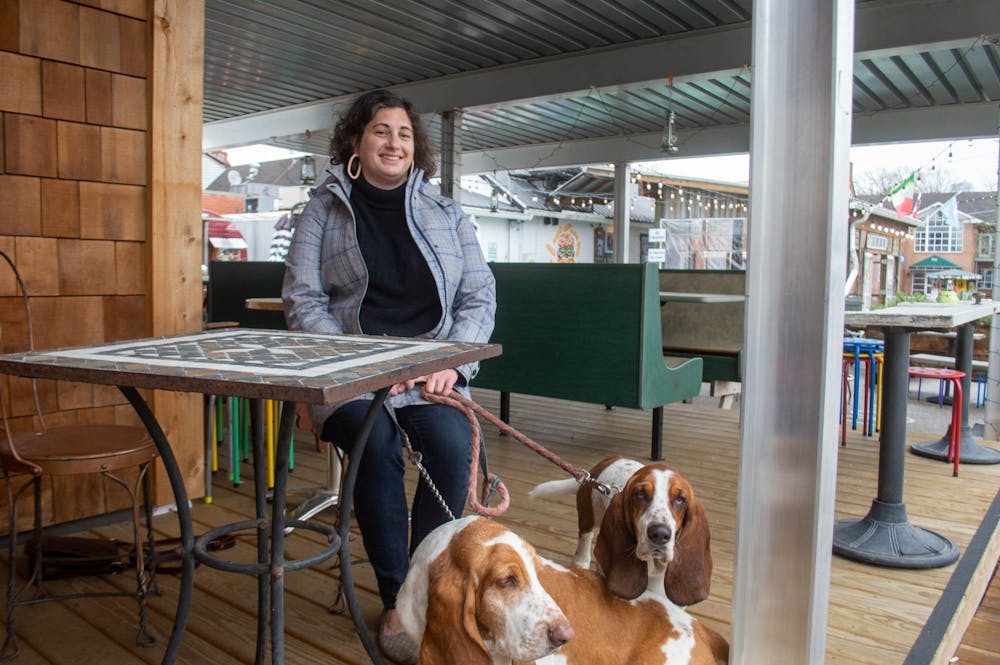 <p>Eleanor Lacy sits outside of her new Chapel Hill restaurant, Bombolo, with her two basset hounds, Claude and Boniface on Wednesday, March 9, 2022. Lacy co-owns Bombolo with her brother, Garrett Fleming, in which they will serve casual Italian food.</p>