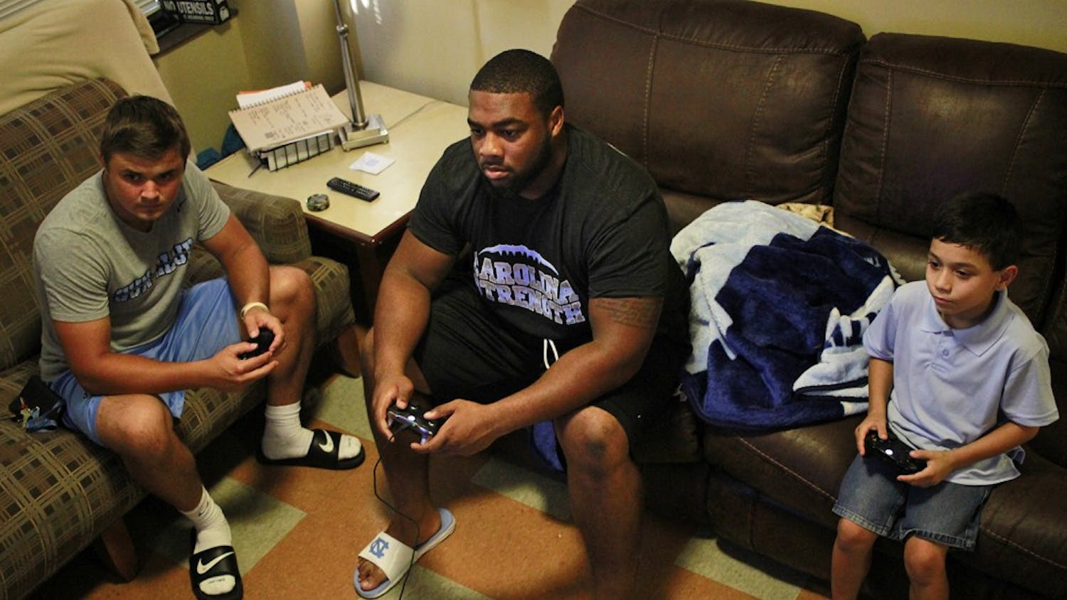 Nathan Elliott (left), a sophomore sports administration major, and Aaron Crawford (middle), a sophomore undecided major, play Xbox with Frankie, Theresa's son (8 years old). 