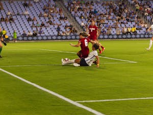 UNC freshman forward Isabel Cox (13)  makes a slide tackle for the ball, stealing from NC State redshirt sophomore defender Lulu Guttenberger (6) in the UNC Soccer and Lacrosse Stadium on Thursday, Sept. 26, 2019.