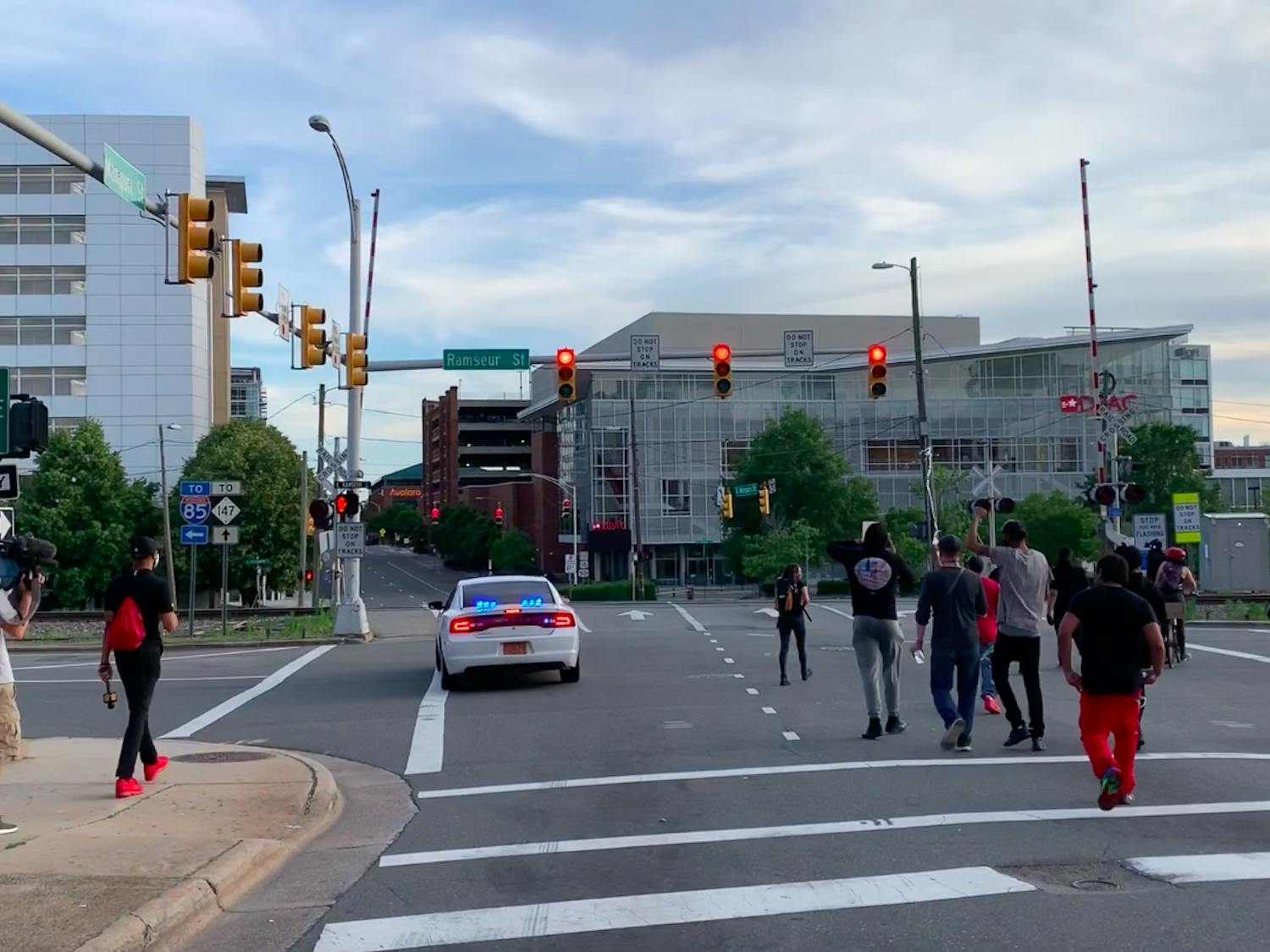 Protestors walk through downtown Durham with a police vehicle in the street on Monday, June 1, 2020.
