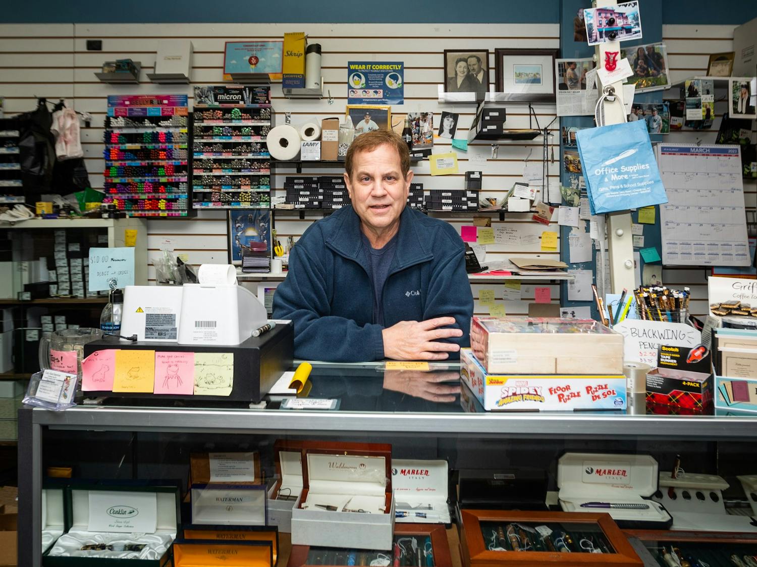 Alan Cohen, owner of Crazy Alan's Emporium, leans on the checkout counter of his store in Chapel Hill, N.C., on Wednesday, March 15, 2023. Crazy Alan's Emporium is an office supplies store that has been in business for over 20 years.