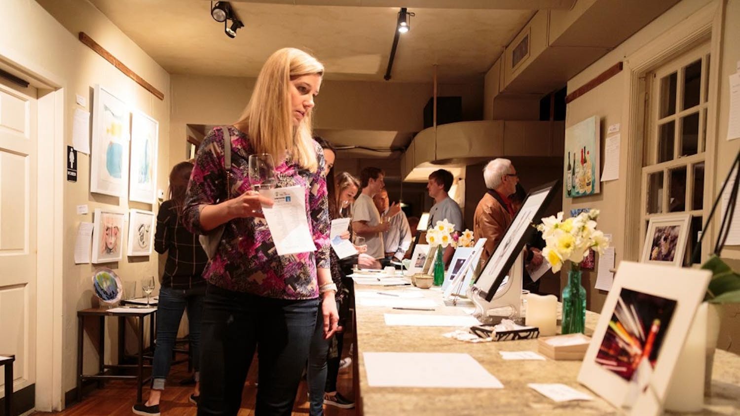 Sarah Yarbrough looks at a table of art at the Mixed Concrete Art Auction on Saturday night.